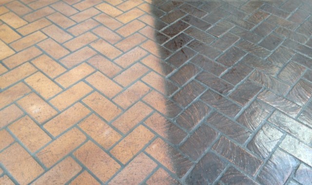 A brick floor with a herringbone pattern and a tile floor.